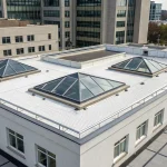 A flat roof with several pyramid skylights bringing natural light indoors.