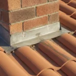 Inspector view of damaged chimney flashing on a tile roof