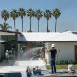 Professional roof coating application on a Southern California home with palm trees and sunny sky